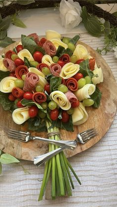 a wooden plate topped with lots of food on top of a table next to utensils