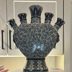 a black vase sitting on top of a table next to a book shelf and cabinets