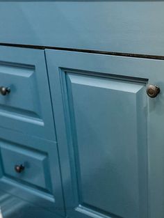 a close up of a blue cabinet with knobs on the door and drawer handles