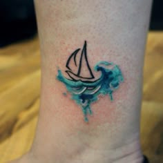 a small sailboat tattoo on the ankle is blue and green watercolors with black ink