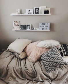 a bed with pillows, blankets and pictures on the wall above it in a bedroom