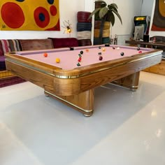 a pool table in the middle of a room with couches and paintings on the wall