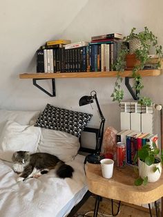 a cat laying on top of a bed next to a wooden table and bookshelf