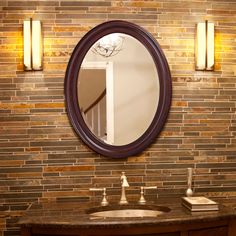 a bathroom sink with a round mirror above it and lights on the wall behind it