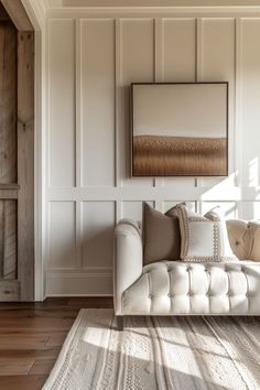 a white couch sitting in a living room next to a wooden wall and flooring