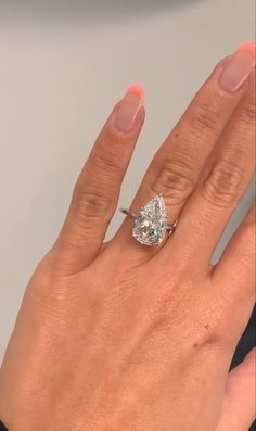 a woman's hand with a diamond ring on top of her finger and the other hand holding an engagement ring