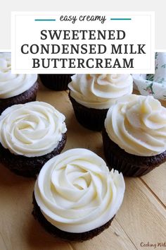 chocolate cupcakes with white frosting sitting on a wooden table