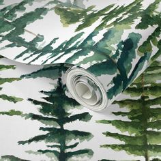 a green and white wallpaper with watercolor trees on it's side, next to a roll of tape