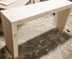 a wooden bench sitting in the middle of a room next to other pieces of wood