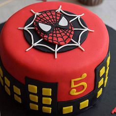 a spiderman themed birthday cake with cupcakes in the background