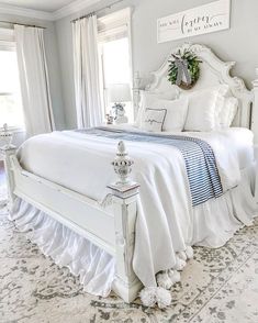 a white bed sitting in a bedroom next to two windows