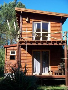 a wooden house with white curtains on the porch