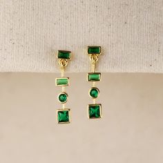 Multi-geometric shapes featuring bezel settings of Emerald Green Cubic Zirconia stones forming gorgeous delicate dangling earrings. Dimension: 1-inch length Shapes: rectangle, circle, square Weight: 3.2 grams - pair Hypoallergenic and water resistant Handcrafted in Brazil Also available in Multicolor Hand Chain Bracelet, 18k Gold Chain, Pearl Shop, Cubic Zirconia Necklace, Hand Chain, Dangling Earrings, Emerald Jewelry, Anklet Jewelry, Earrings Collection