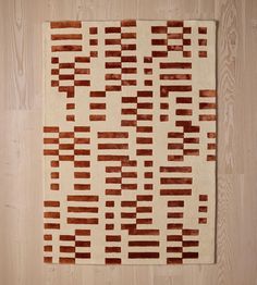 a brown and white area rug on top of a wooden floor next to a wall