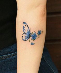 a blue butterfly and flowers tattoo on the arm