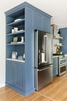 a kitchen with blue painted cabinets and stainless steel appliances in the center, along with wooden flooring