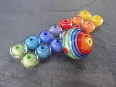 a group of colorful glass beads sitting on top of a cement floor next to each other