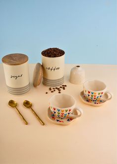 three cups with spoons, two salt and one pepper shaker on a table