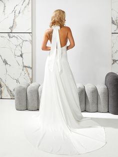 a woman in a white dress is looking at the back of her wedding dress,