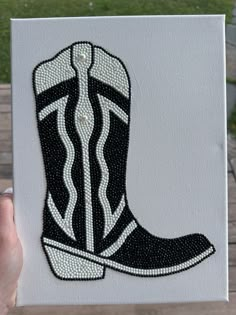 a hand holding up a black and white cowboy boot with diamonds on it's side