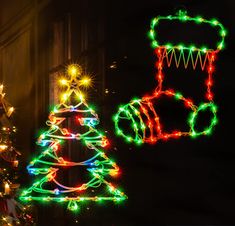 two christmas trees with lights on them in front of a building