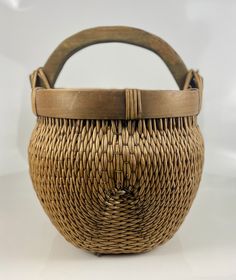 a woven basket with wooden handles on a white surface