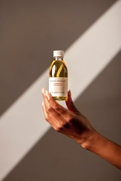 a person's hand holding a bottle of oil