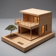 a wooden model of a house with a tree in the front and two windows on each floor