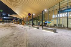 an empty street in front of a building with glass walls and lights on the side