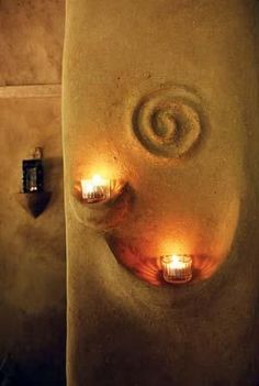 two candles are lit on the side of a stone wall in a bathroom that looks like a spiral