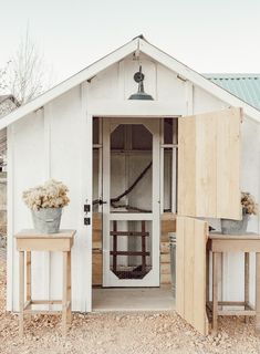 a white shed with two small tables in front of it