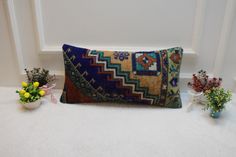 a decorative pillow sitting on top of a white floor next to flowers and potted plants