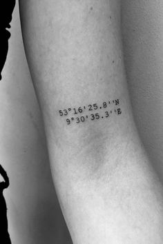 a woman's arm with the coordinates tattoo on her left forearm and numbers in black ink