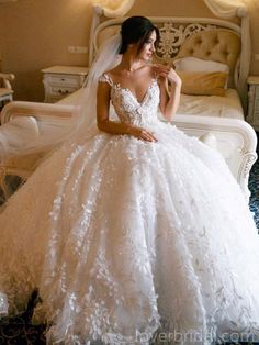 a woman in a white wedding dress sitting on a bed with her hand on her shoulder