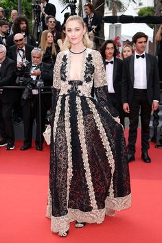 a woman in a black and white dress standing on a red carpet with photographers behind her