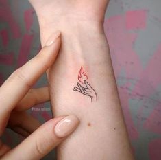 a woman's arm with a small tattoo on her left wrist and the word love written in red ink