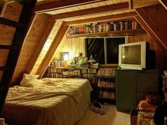 an attic bedroom with bookshelves and a tv in the corner next to a bed