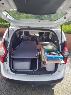 the back end of a white van with open hatchback doors and luggage in it