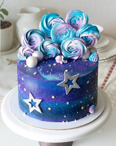 there is a blue and purple cake with stars on the top that has icing