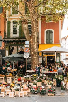 an outdoor market with tables and umbrellas on the side walk in front of buildings