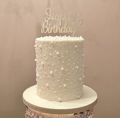 a white birthday cake with pearls on it