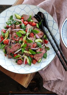 a white plate topped with meat and veggies on top of a wooden table