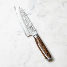 a large knife on top of a white counter next to a silver and wood handle