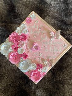 a pink and white graduation cap with flowers on it sitting on a furnishing