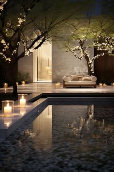 candles are lit in front of a pool at night with trees and flowers around it