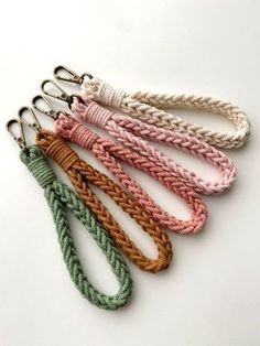 four different colored rope key chains on a white surface