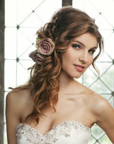 a woman with long hair wearing a wedding dress and flower in her hair is posing for the camera