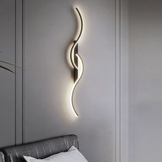 a wall mounted light that is on the side of a wall next to a bed