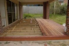 a wooden deck under a house with brick pillars