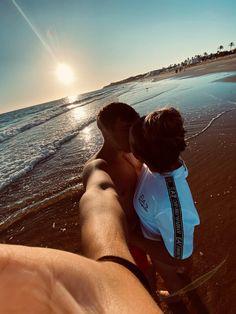 a man and child are on the beach looking at the ocean while holding each other